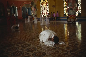 VIETNAM, Tay Ninh Province, Adherants at prayer in Cao Dai Temple