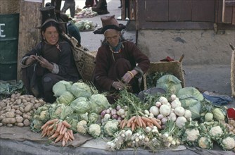 INDIA, Ladakh, Leh, Women wearing traditional hats selling vegetables at market.