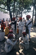 INDIA, Rajasthan, Pushkar, Group of men in shade of tree during midday heat at annual fair.