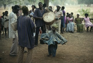 GHANA, North, Tamale, Small child dancing to drumming musicians at wedding.