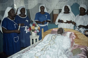 GHANA, South, Teshie, Women surround deceased Ga priestess of the sea god Kanjar laid out on bed