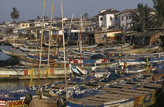 GHANA, Elmina, Moored fishing boats and waterfront buildings.