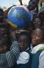 MALAWI, Blantyre, Children holding papier mache globe teaching aid made by PAMET from recycled