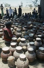 CHAD, Habila, Woman selling vessels of Marissa Beer made from Sorghum and millet at Chadian Refugee