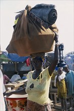 GUINEA, Kissidougou, Camp for Sierra Leonean Refugees. Woman carrying sack on her head arriving in