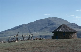 LESOTHO, Architecture, Circular straw roofed hut with mountains behind