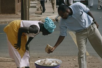 GAMBIA, Markets, Woman selling Cashew nuts to a man along the road side