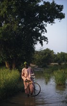 GAMBIA, People, Men, Man with bicycle wading through water