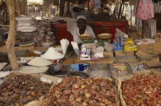 SUDAN, North Darfur, El Fasher, Market trader sitting behind scales and display of dried foodstuffs
