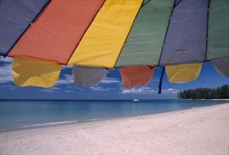 THAILAND, North Phuket, Naiyang Beach, "Close up of a multi coloured parasol on the sandy beach,