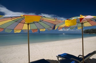 THAILAND, North Phuket, Naiyang Beach, "Two multi coloured parasols and  sun loungers on the sandy