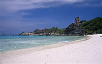 THAILAND, Koh Similan , Sail Rock, View along the sandy beach with people and boats near the rocky