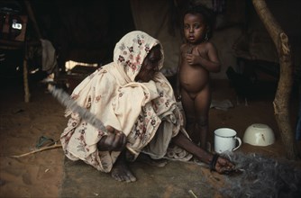 SUDAN, North Kordofan, Work, Kababish nomad woman spinning wool inside hut with little girl