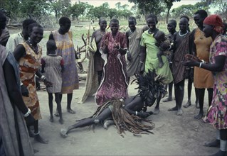 SUDAN, Tribal People, Dinka Binzar or witch doctor wearing head-dress of feathers on ground in
