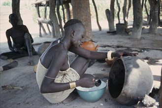 SUDAN, Tribal People, Dinka woman cooking with oil from shea butter fruit.