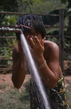 LAOS, Water, Child in Hmong village washing with water from UNHCR supplied tap.