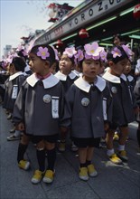 JAPAN, Honshu, Tokyo, Asakusa. Kannon Temple.Nursery school children dressed in uniforms and flower