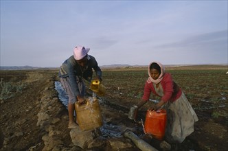 ERITREA, Seraye Province, Women collecting water at irrigation pipe.