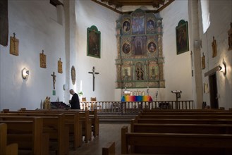 USA, New Mexico, Santa Fe, The altar and nave of the San Miguel Mission church with a priest