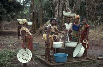 NIGERIA, Mid West State, Ibo, Women collecting water from well standpipe.