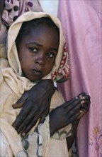 SUDAN, Asernei, Portrait of Chadian refugee girl standing beside her partly seen mother.