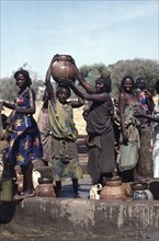 SUDAN, Habila Settlement, Group of Chadian refugee women collecting water from well.