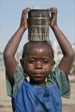 GUINEA, Kissidougou Camp, Portrait of Sierra Leonean refugee girl carrying can of water on her head
