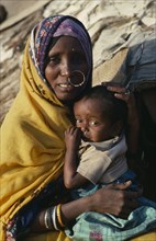 SUDAN, North East, Gadem Gafriet Camp, "Portrait of Beni Amer Beja nomad woman holding child,