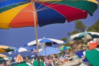SPAIN, Balearic Islands, Ibiza, Parasols and sunbathers on the beach at Portinatx.