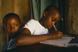 RWANDA, Akagera, "Children of Tutsi returnee family doing homework.  The family fled to Uganda over
