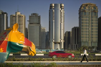 UAE, Abu Dhabi, "City centre skyline along the Corniche. Statue of a colourful patchwork camel, red