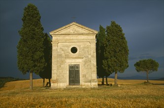 ITALY, Tuscany, Small stone chapel and cyrpress trees near San Quirico d’Orcia.