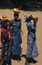 NIGER, People, Girls, Girls wearing brightly coloured dresses selling tomatoes carried in bowls on