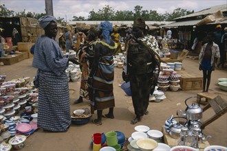 NIGER, Sahel, Niamey, Busy market scene with group of women looking at cooking utensils and pots in