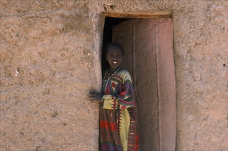 NIGER, Fachi, Young girl looking out of doorway of mud brick building.