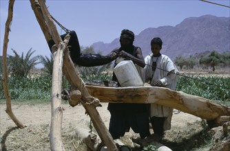 NIGER, Air Mountains, Tuareg filling water bottles for agricultural use.