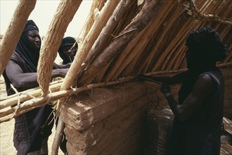 NIGER, Architecture, Tuaregs building home using mud bricks and branches for main structure.