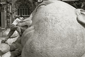 FRANCE, Ile de France, Paris, A child plays on the statue of a reclining Buddha.