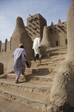 MALI, Sahel, Djenne, Two men walking up steps leading to Grand Mosque.