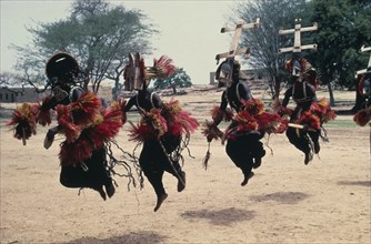 MALI, Ceremony, Dogon masked dancers leaping in line.