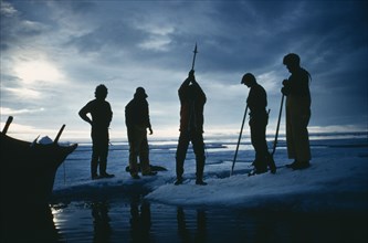 ARCTIC, Eskimos, "Silhouette of a man using an axe to cut through ice. Others stand round, two