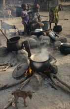 MALI, Food, Woman cooking on open fires in village compound with children and goats.