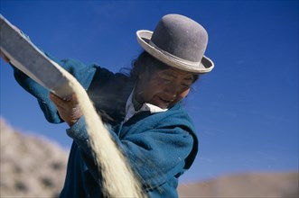 BOLIVIA, Altiplano, Potosi, "Salar de Uyuni, Manica Town.  Woman winnowing quinoa."