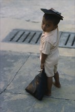 MYANMAR, Yangon, Portrait of young child standing on pavement.