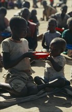 MOZAMBIQUE, Zambezia Province, Mugulama, Children sharing bowl at feeding centre for displaced