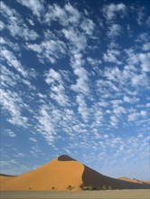 NAMIBIA, Namib Desert, Sossusvlei, Sand dune with dramatic clouds scattered in a blue sky above