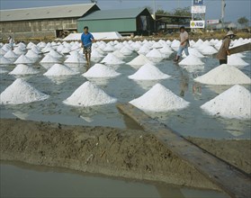THAILAND , Ratchaburi Province, Three people working at Salt pans outside Bangkok on the road to