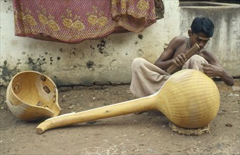 INDIA, Tamil Nadu, Tanjore, "Instrument maker finishing a veena, a traditional stringed instrument