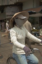 VIETNAM, South, Ho Chi Minh City, Woman wearing a conical hat with a scarfe covering her mouth