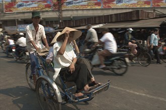 VIETNAM, South, Ho Chi Minh City, Two women riding a Cyclo on a busy street